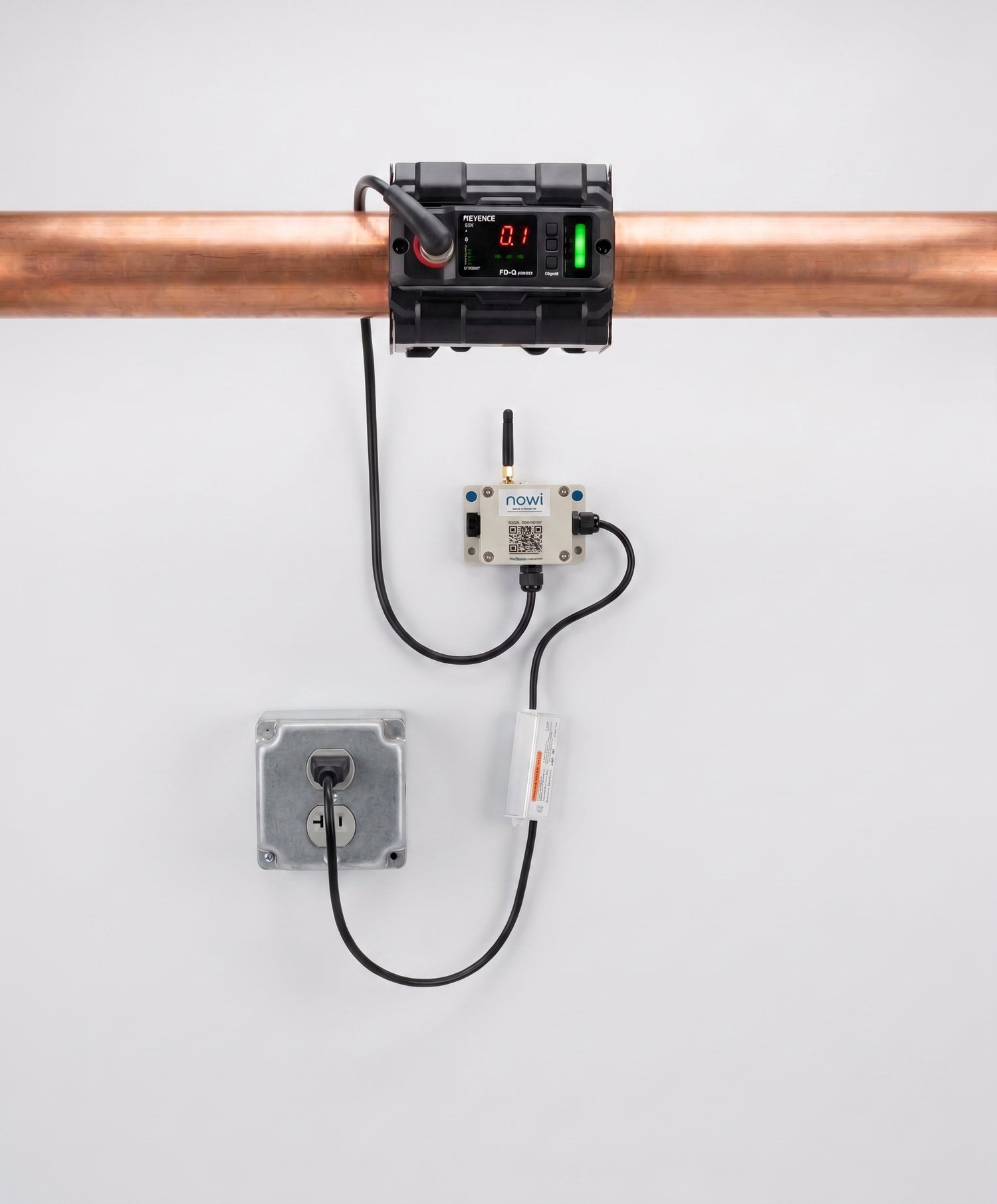 NOWi Pipe Monitor installed on a copper pipe: Keyence ultrasonic flow sensor, NOWi cellular communication box, and power supply